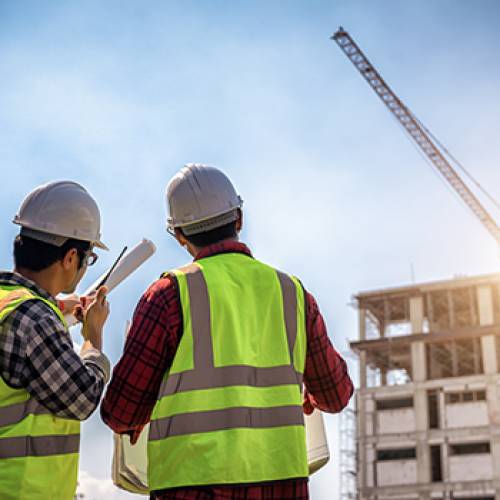 Two construction workers surveying a commercial construction project