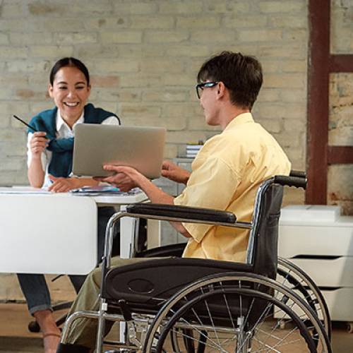 Man in wheelchair consults with coworker