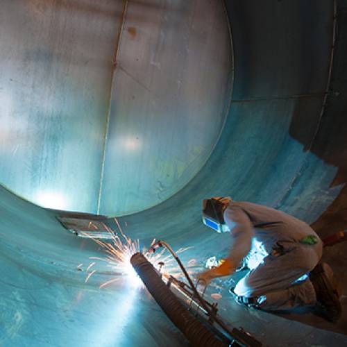 Welder working inside a large metal tube welding