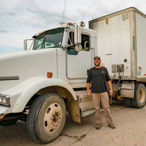 Driver stands in front of a commercial truck