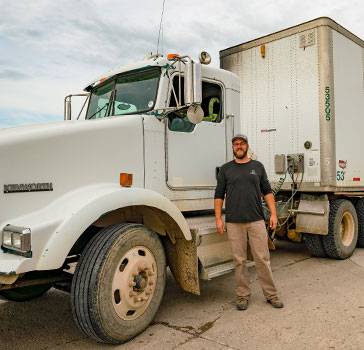 Driver stands in front of a commercial truck