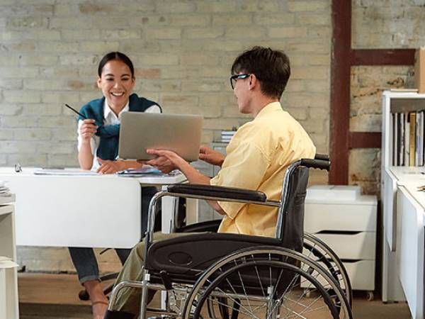 Man in wheelchair consults with coworker