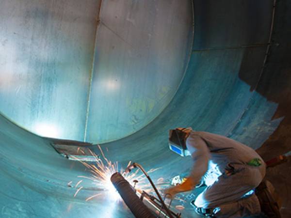 Welder working inside a large metal tube welding