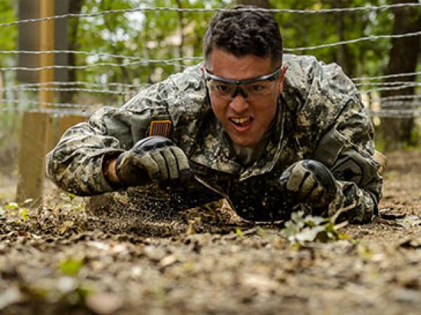 A soldier crawls through a portion of an obstacle course