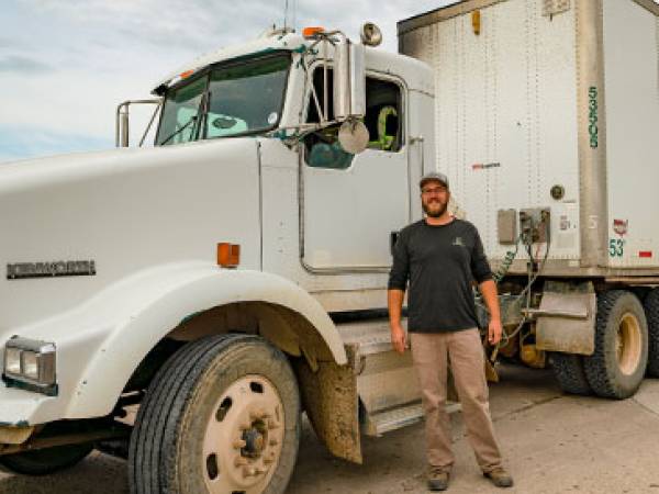 Driver stands in front of a commercial truck