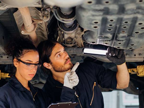 Apprentice looking at the undercarriage of a vehicle 
