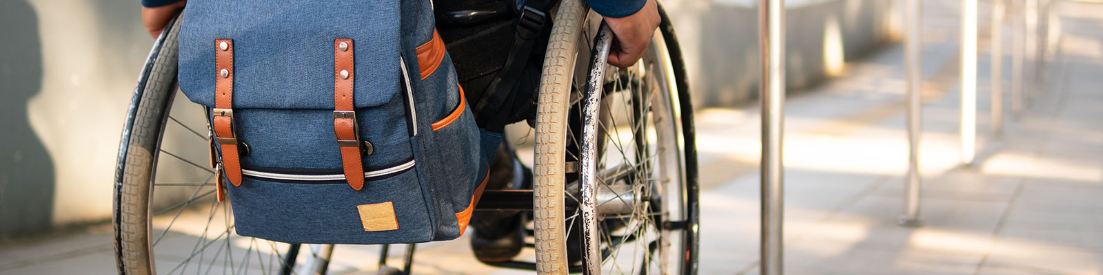 Closeup of wheelchair wheels with a ramp in the background