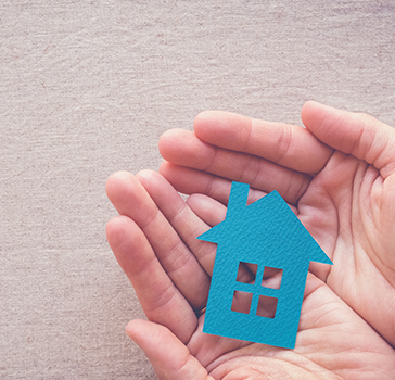 Hands holding a paper house cutout