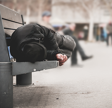 Homeless man sleeping on a public bench