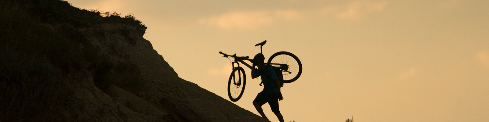 Man carrying bike up a steep part of the Maah Daah Hey Trail