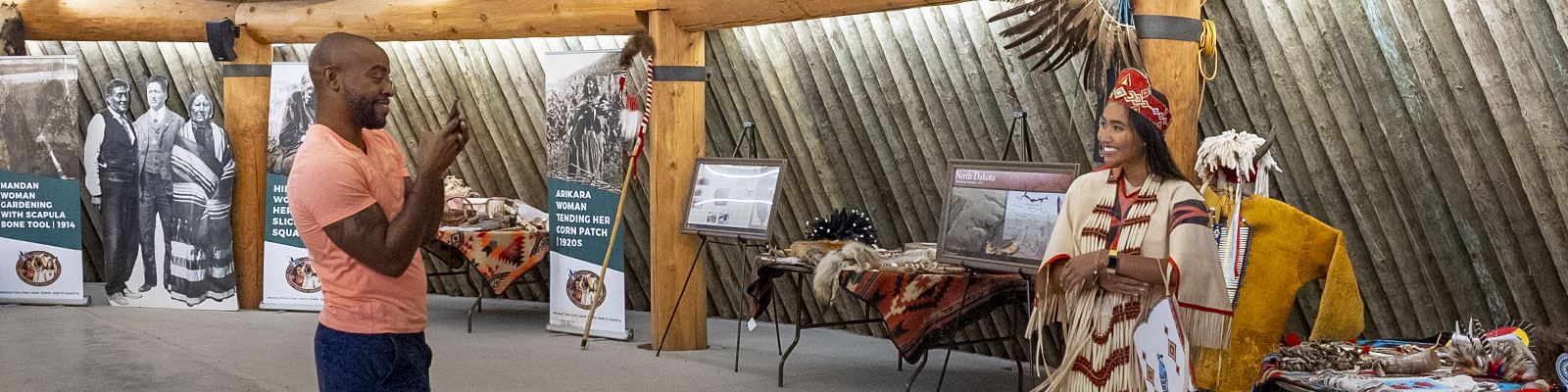 Couple take a picture while trying on some of the items at the MHA Earth Lodge Village