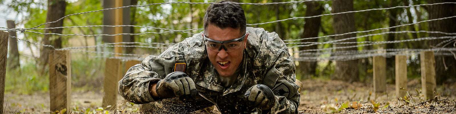 Soldier crawls through a portion of the obstacle course at Camp Grafton 