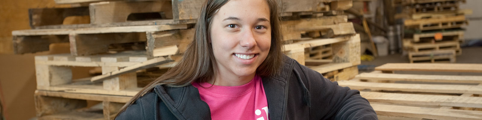 Female intern poses in front of pallets