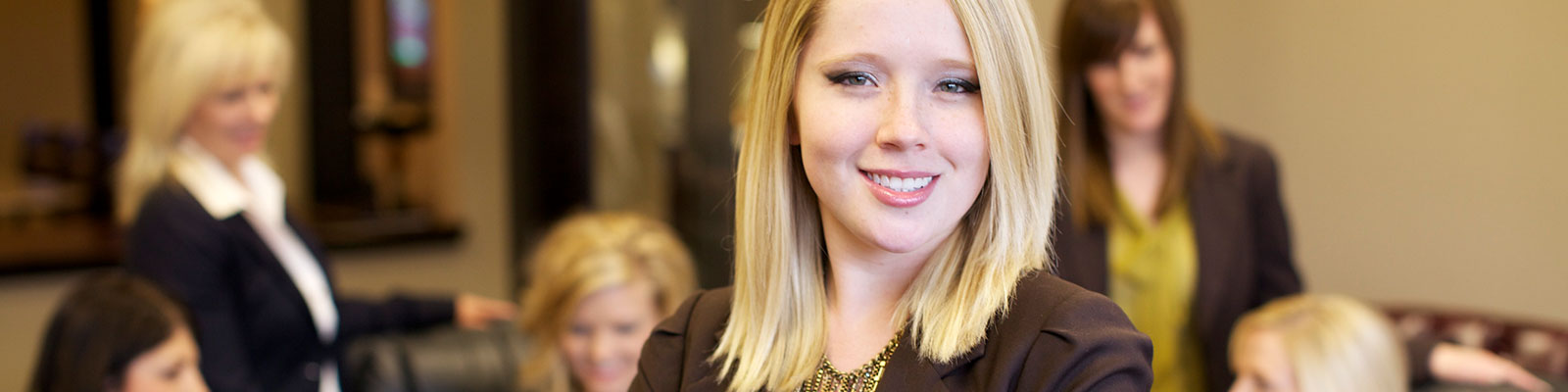 Woman poses in front of coworkers in a conference room