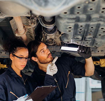 Apprentice looking at the undercarriage of a vehicle 