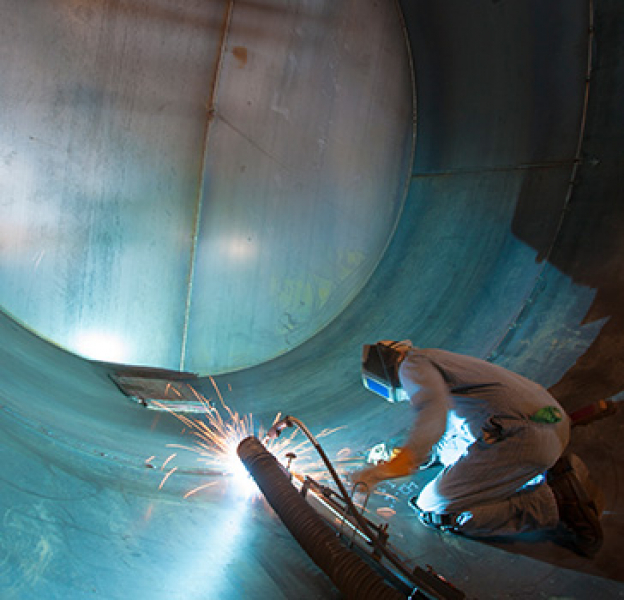 Welder working inside a large metal tube welding