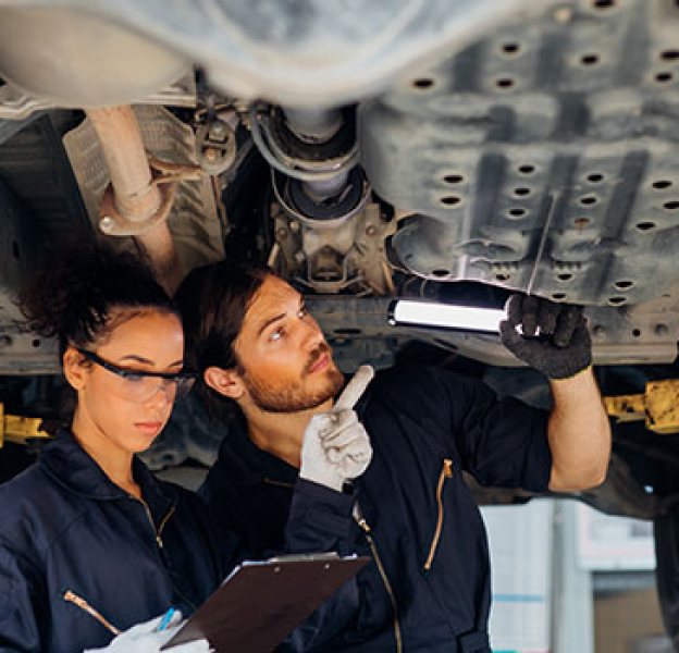 Apprentice looking at the undercarriage of a vehicle 